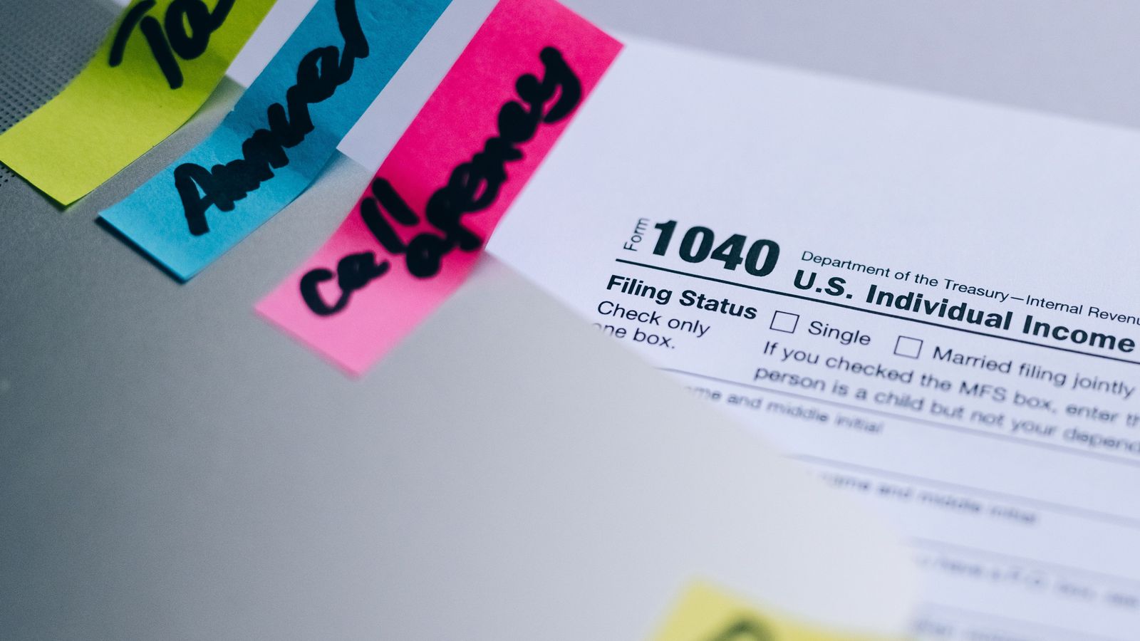 U.S. tax form 1040 with colorful sticky notes on a desk.